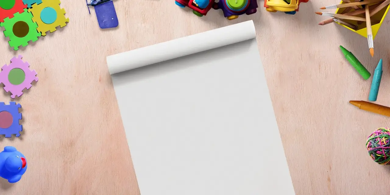 Kolorowe zabawki, kredki i pędzle na drewnianym tle, gotowe do stworzenia materiałów dla nauczycieli.