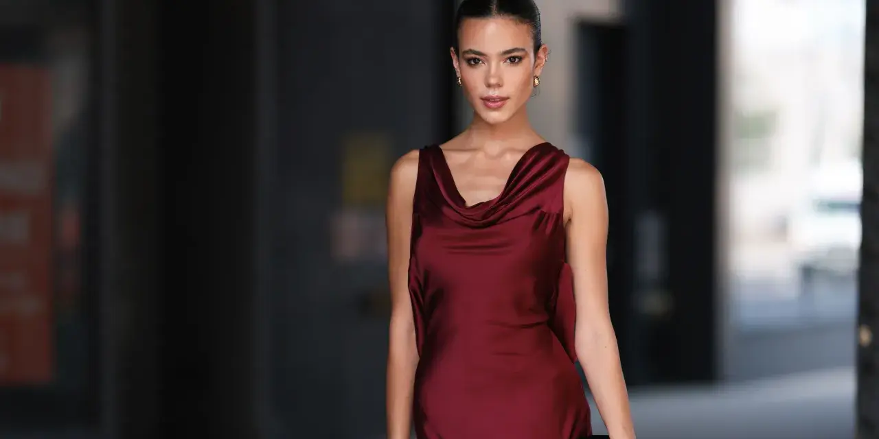 Una mujer elegante con un vestido burdeos satinado, ideal para saber como combinar un vestido burdeos para una boda.