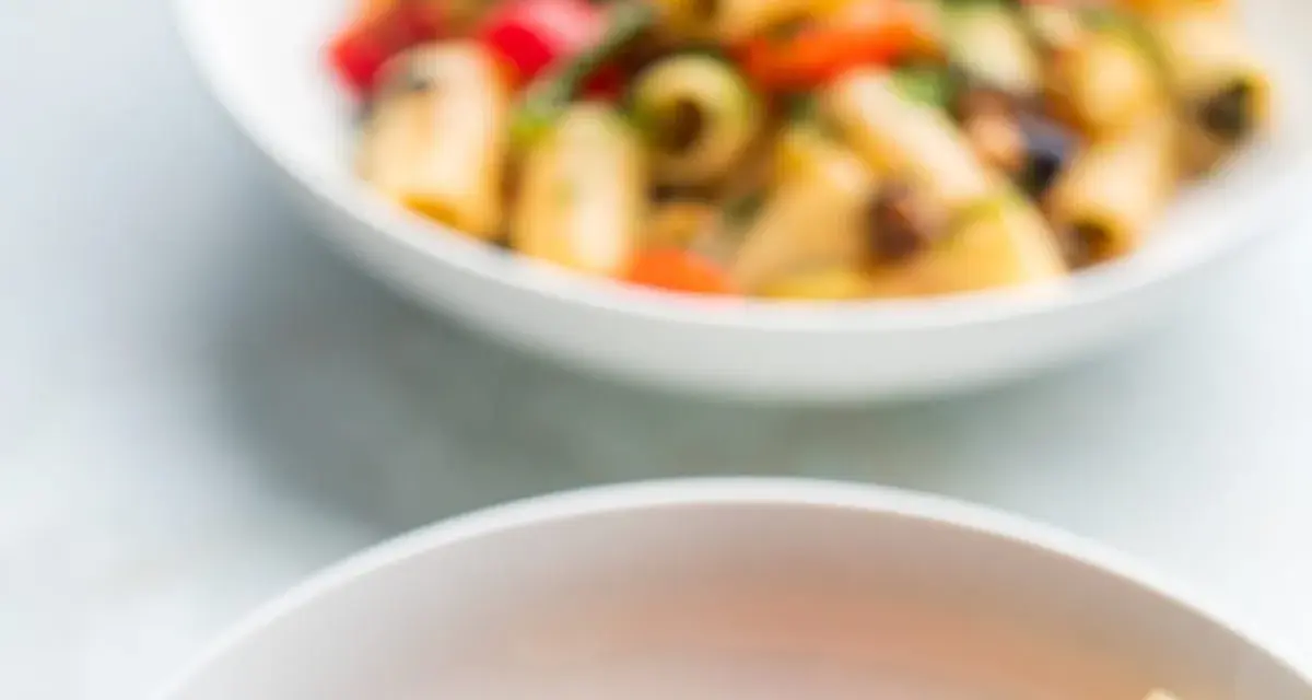 Due ciotole bianche piene di pasta con verdure colorate, un piatto estivo invitante.