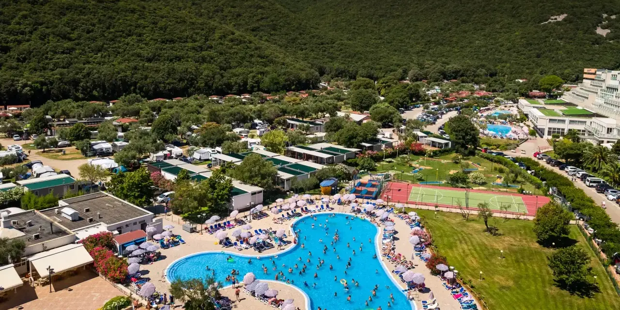 Wakacje na **camping Oliva** to baseny, korty tenisowe i mnóstwo zieleni pod górą.
