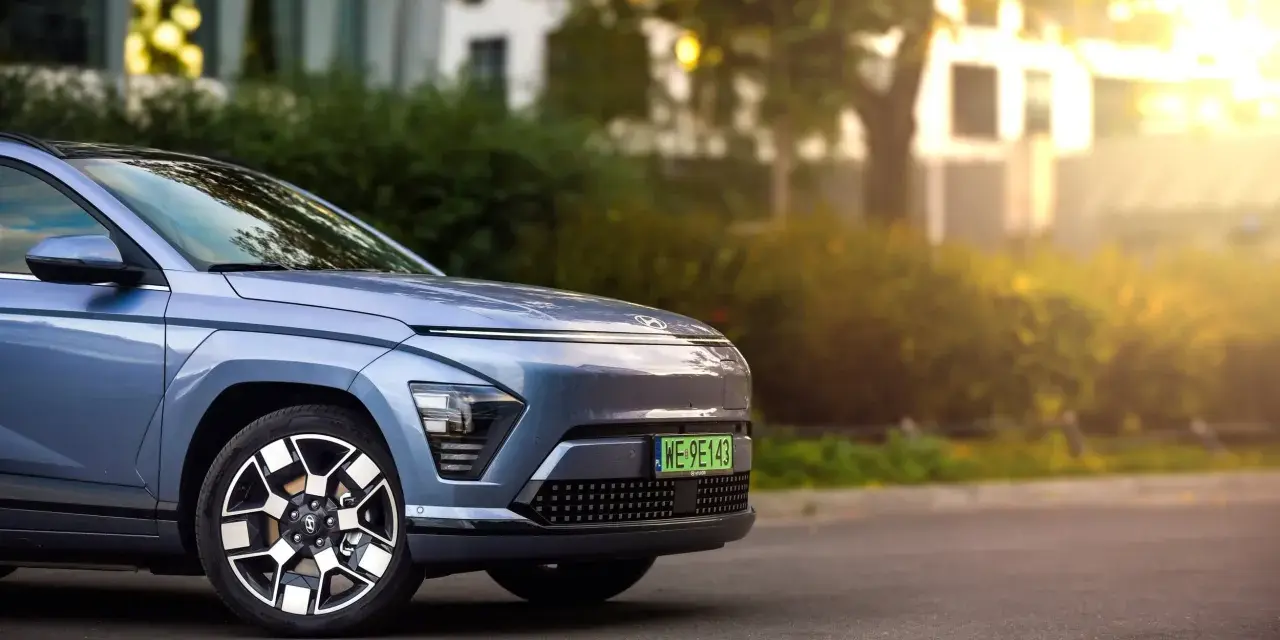 Niebieski Hyundai Kona Electric zaparkowany na ulicy, z widocznym przodem i kołem.