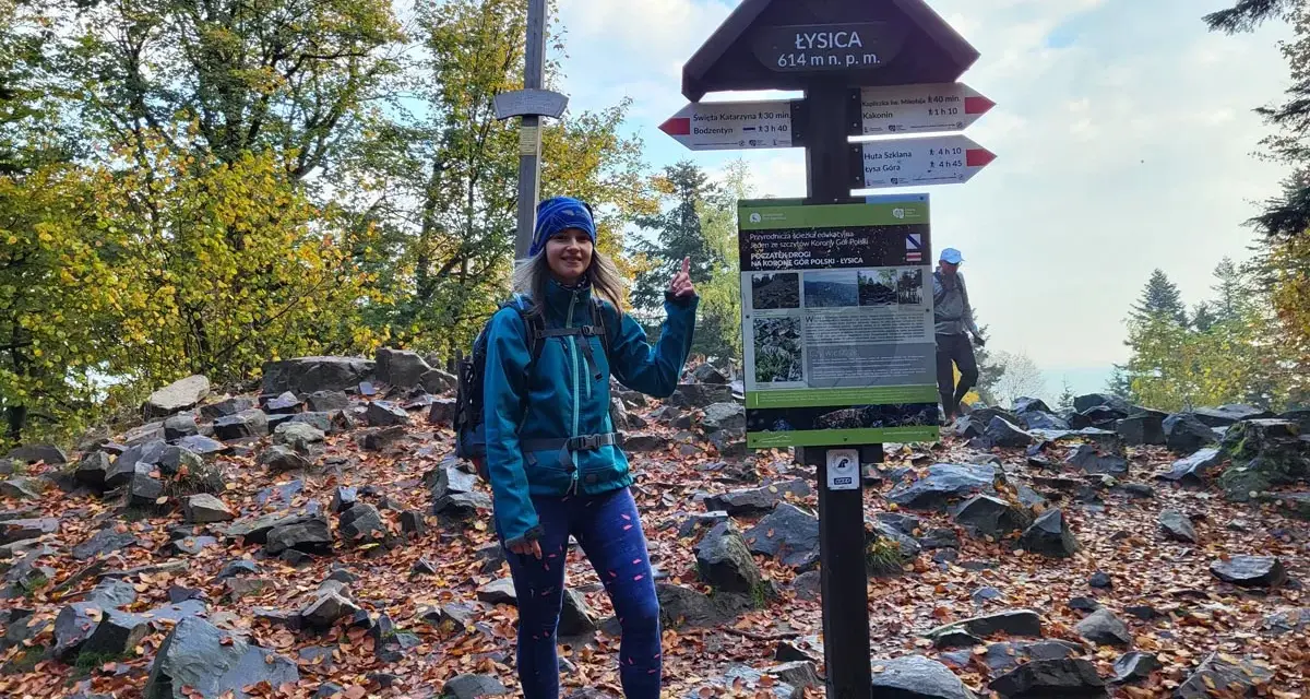 Kobieta na szczycie Łysicy, 614 m n.p.m., z drogowskazem. Jesienny szlak na Łysicę wita turystów.