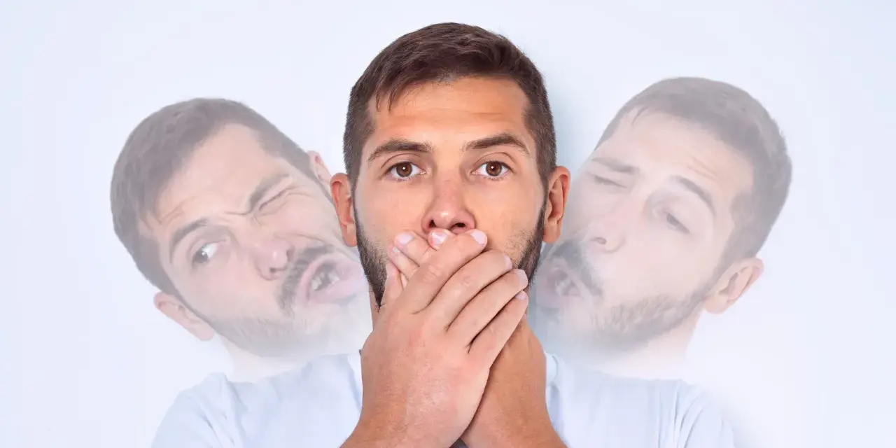Mężczyzna z zespołem Tourette'a zakrywa usta, próbując powstrzymać tiki.