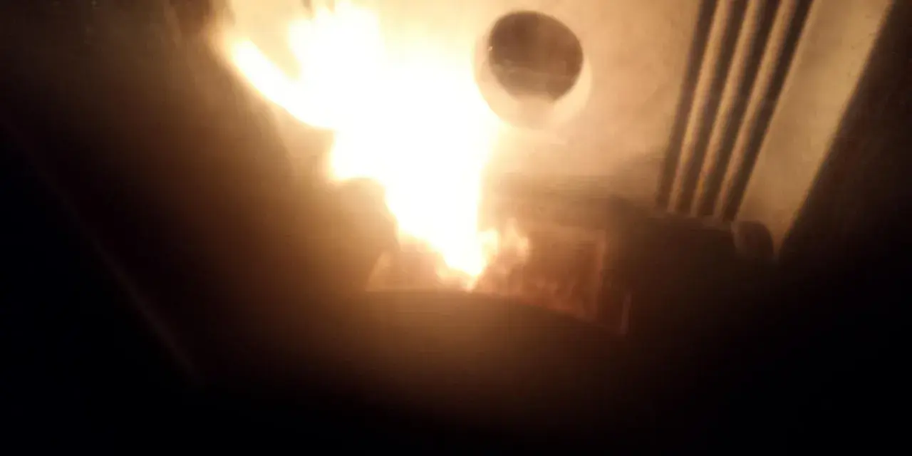Flammes vives dans un poêle Piazzetta, peut-être un problème de tirage. La chaleur intense illumine l'intérieur.
