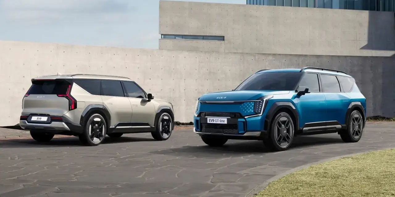 Dwa samochody elektryczne Kia EV9 w kolorach niebieskim i jasnoszarym stoją na zewnątrz.