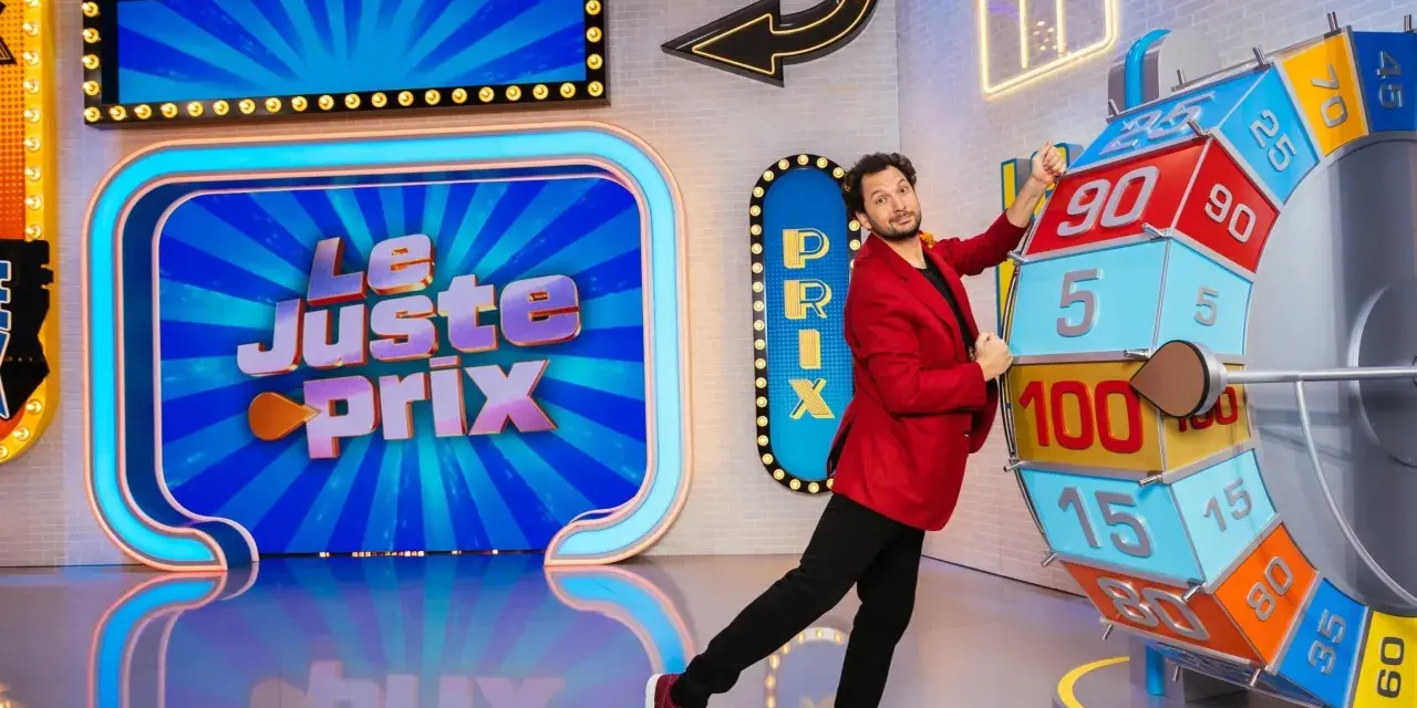 Un animateur pose près de la roue du jeu "Le Juste Prix". L'illustration du plateau est colorée et lumineuse, promettant de beaux gains.