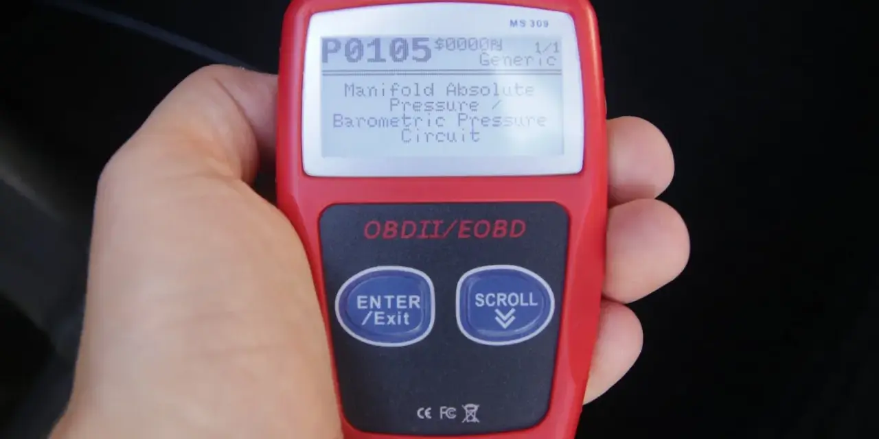 Ręka trzyma czytnik OBD, wyświetlający kod błędu P0105: "Manifold Absolute Pressure / Barometric Pressure Circuit". To jeden z wielu kodów błędów OBD po polsku.