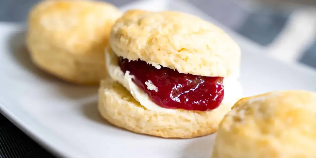 Frisch gebackene Scones mit Clotted Cream und Erdbeermarmelade, ein köstliches Rezept für den Nachmittagstee.