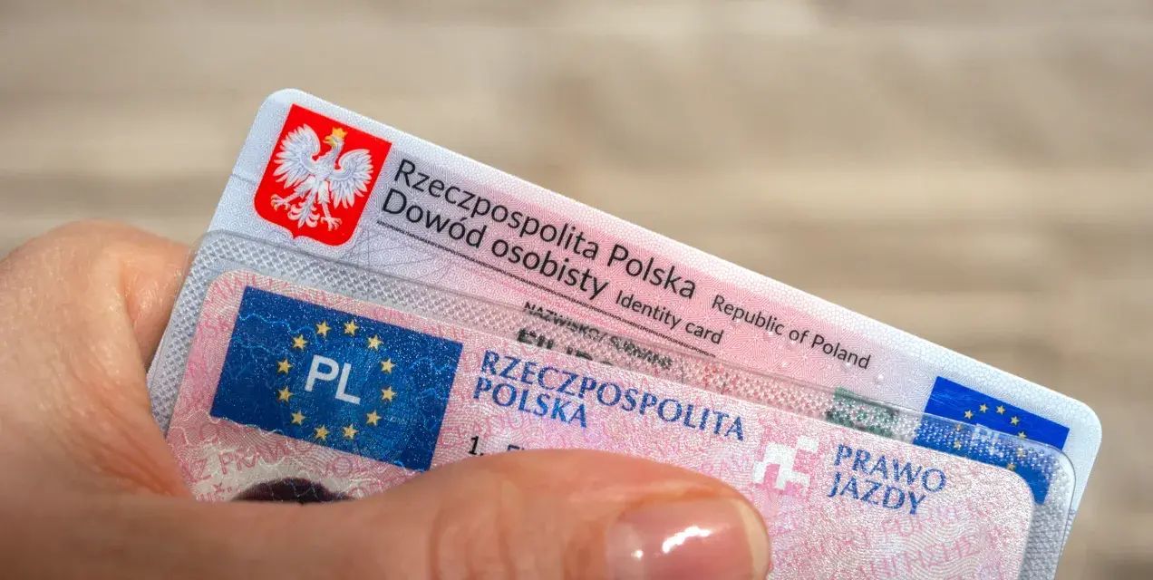 Dłoń trzyma polski dowód osobisty i prawo jazdy.