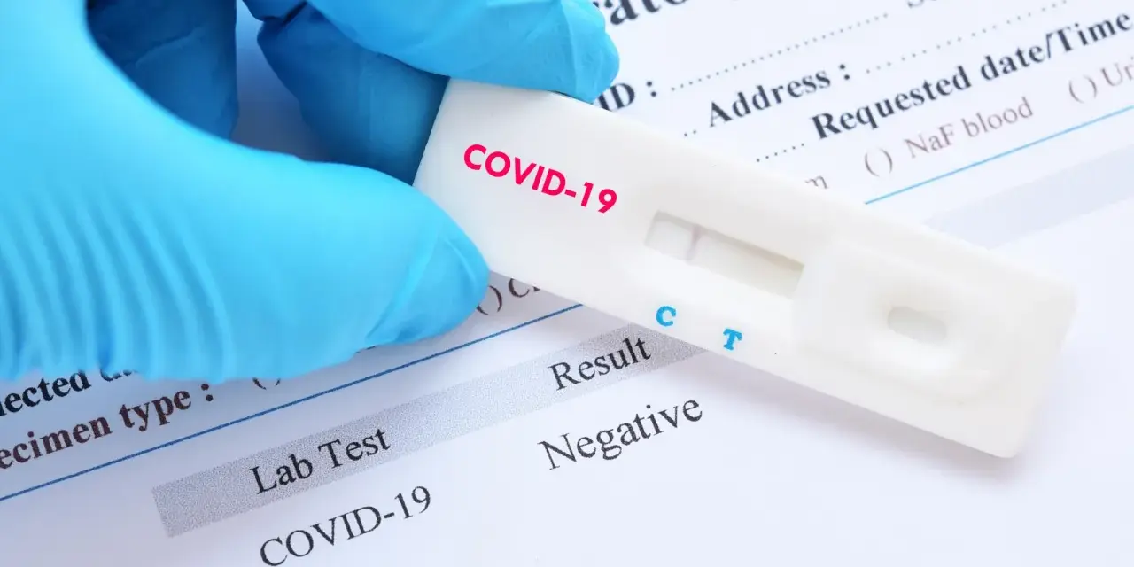 Rękawiczka w niebieskiej rękawiczce trzyma test na COVID-19 z negatywnym wynikiem. Zastanawiasz się, ile kosztuje test na covid?