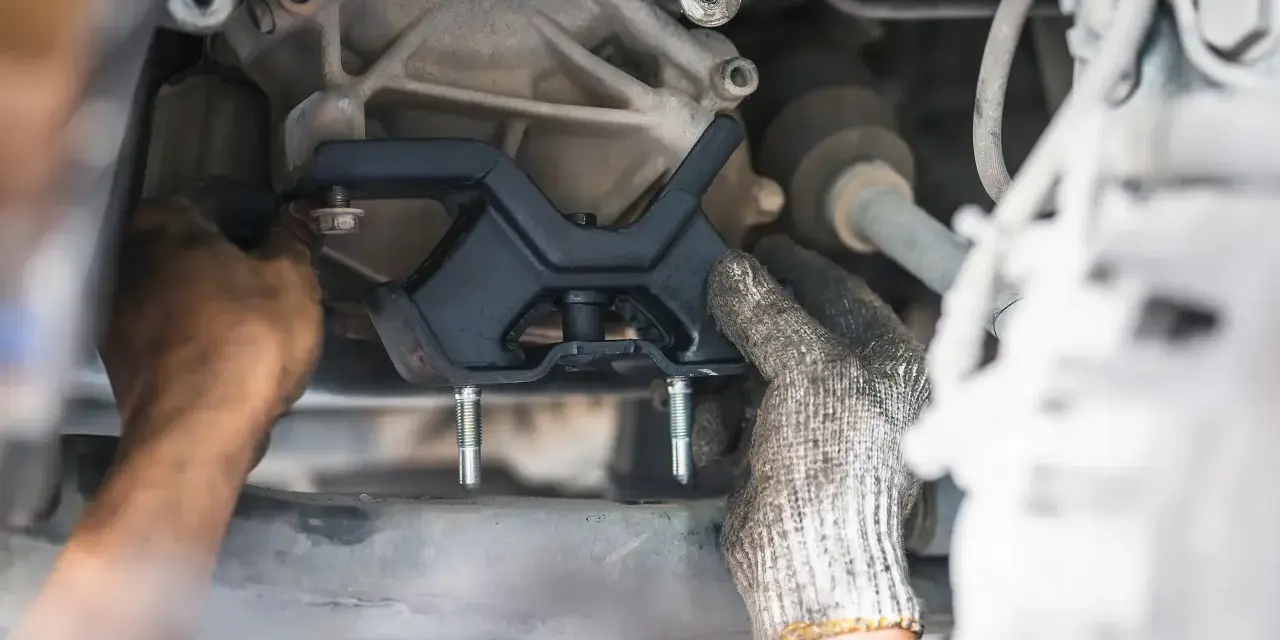 Mechanic installing a new engine mount. This repair is essential for smooth driving and can impact motor mount replacement cost.