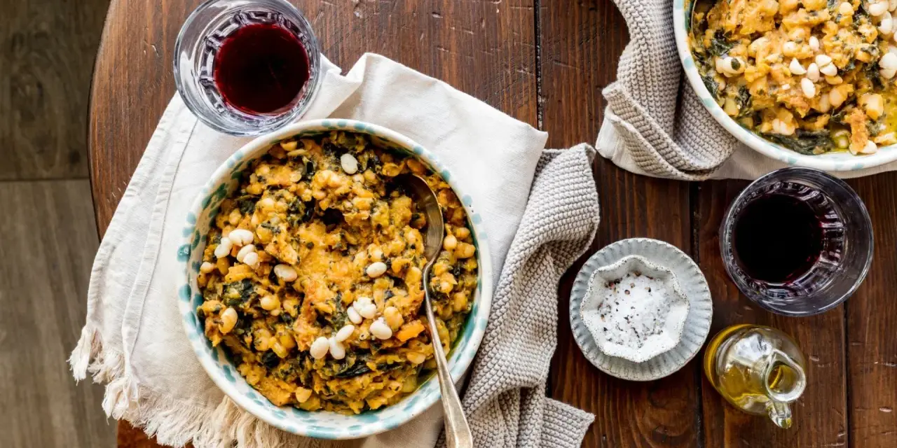 Un piatto di fagioli e verdure, un classico esempio di cose tipiche toscane, accompagnato da vino rosso e olio.
