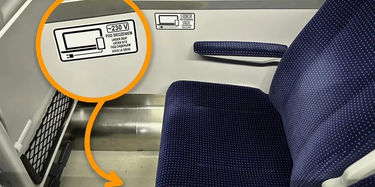 Na siedzeniu w TLK jest naklejka informująca, że pod siedzeniem znajdują się gniazdka 230V.