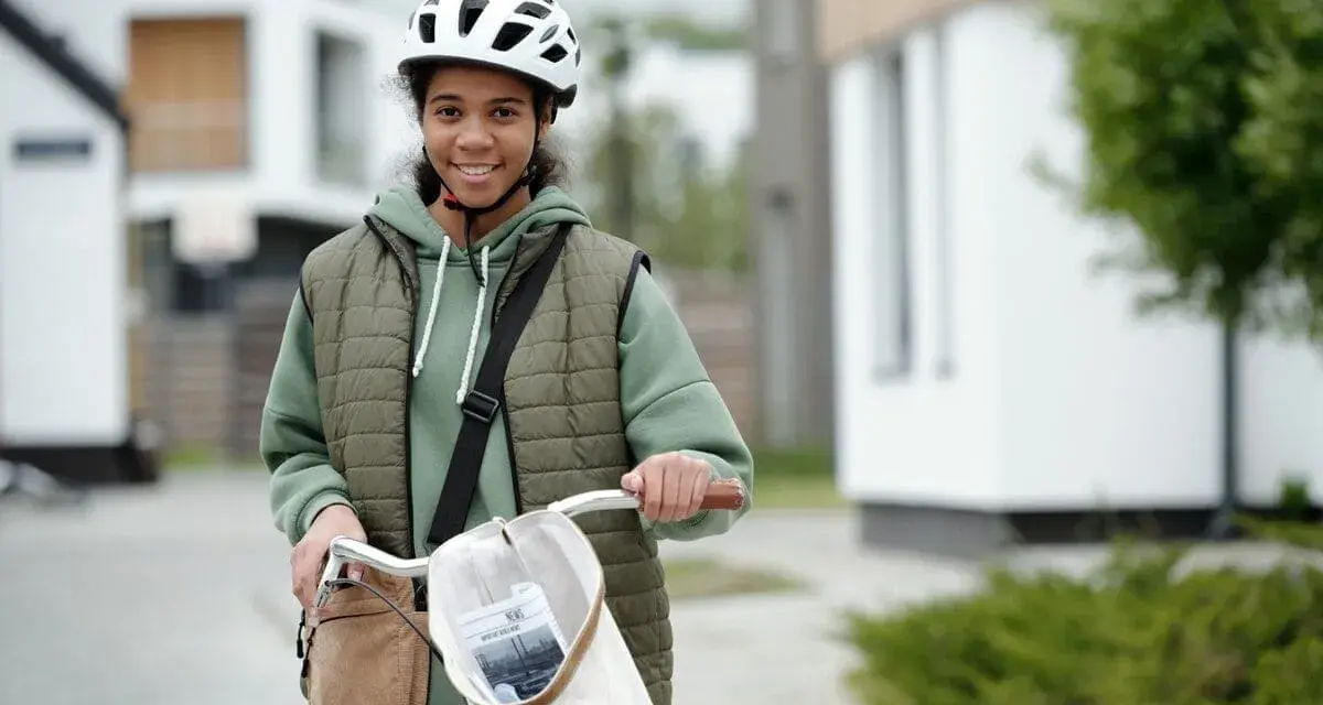 Junges Mädchen mit Fahrrad und Helm, bereit für ihre ersten jobs ab 14. Sie lächelt optimistisch in die Kamera.
