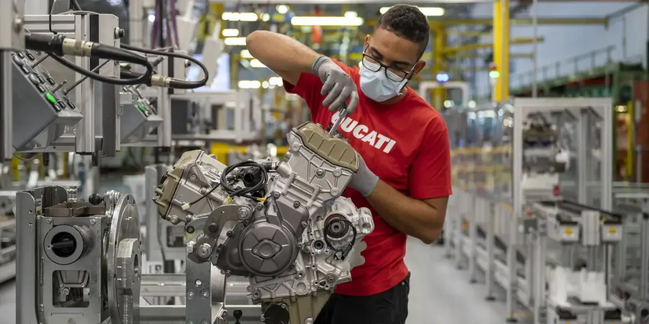 Operaio con mascherina e guanti lavora su un motore Ducati in fabbrica. Un'emozione da museo.