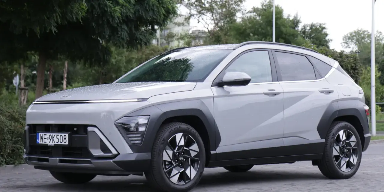 Szary Hyundai Kona Hybrid stoi na zewnątrz, z widocznym przodem i bokiem.