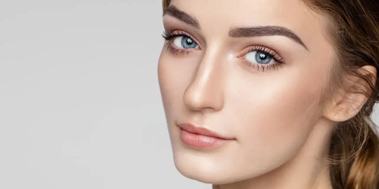 Delikatne rysy twarzy, podkreślone subtelnie zaznaczone mięśnie brody, błękitne oczy i perfekcyjny makijaż.