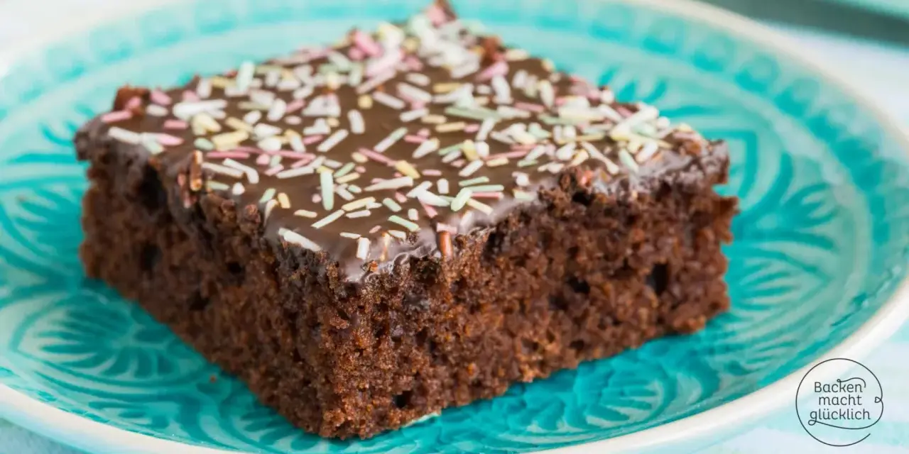 Ein Stück saftiger Schokoladen-Blechkuchen mit Schokoladenglasur und bunten Streuseln auf einem türkisfarbenen Teller. Ein einfaches Blechkuchen Rezept für Glücksmomente.