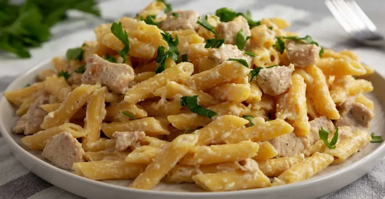 Penne z kurczakiem w kremowym sosie, posypane natką pietruszki. Pyszne danie, które zadowoli każdego miłośnika makaronu.