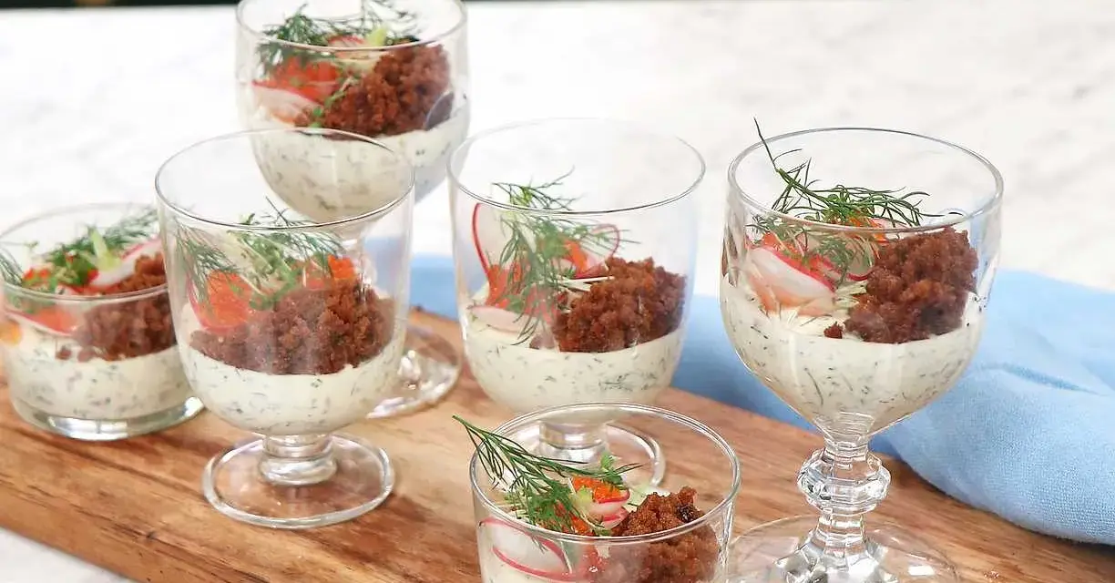 Små glas med silltårta kavring, krämig sås, rom, rädisa och dill. En festlig förrätt.