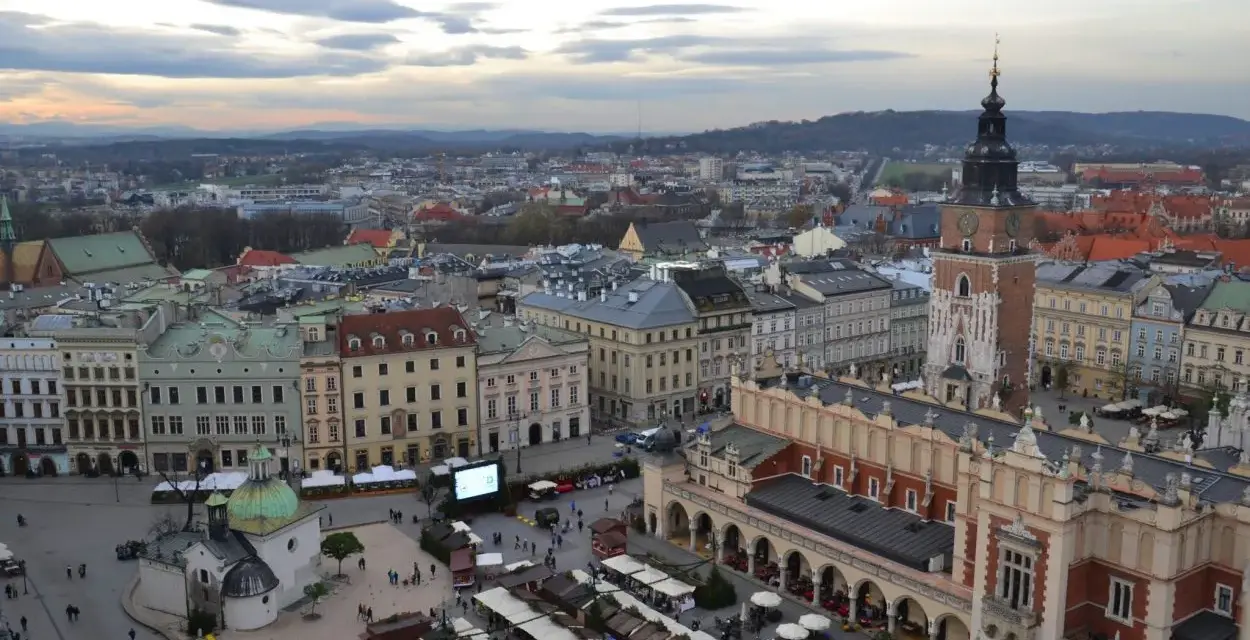 Widok na Rynek Główny w Krakowie z dominującą wieżą Mariacką. W dole kramy jarmarku, Sukiennice i kościółek.