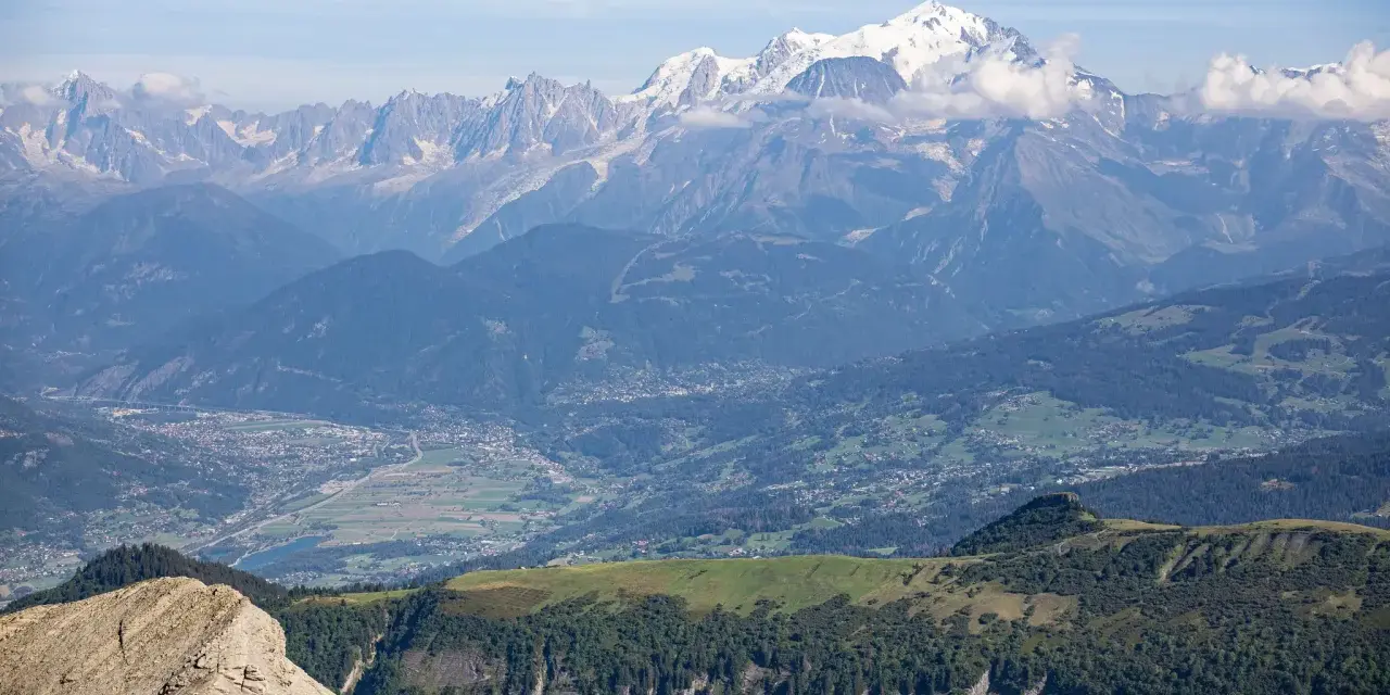 Vue panoramique des Alpes, avec le Mont Blanc enneigé, point culminant des Alpes, dominant la vallée verdoyante et ses villages.