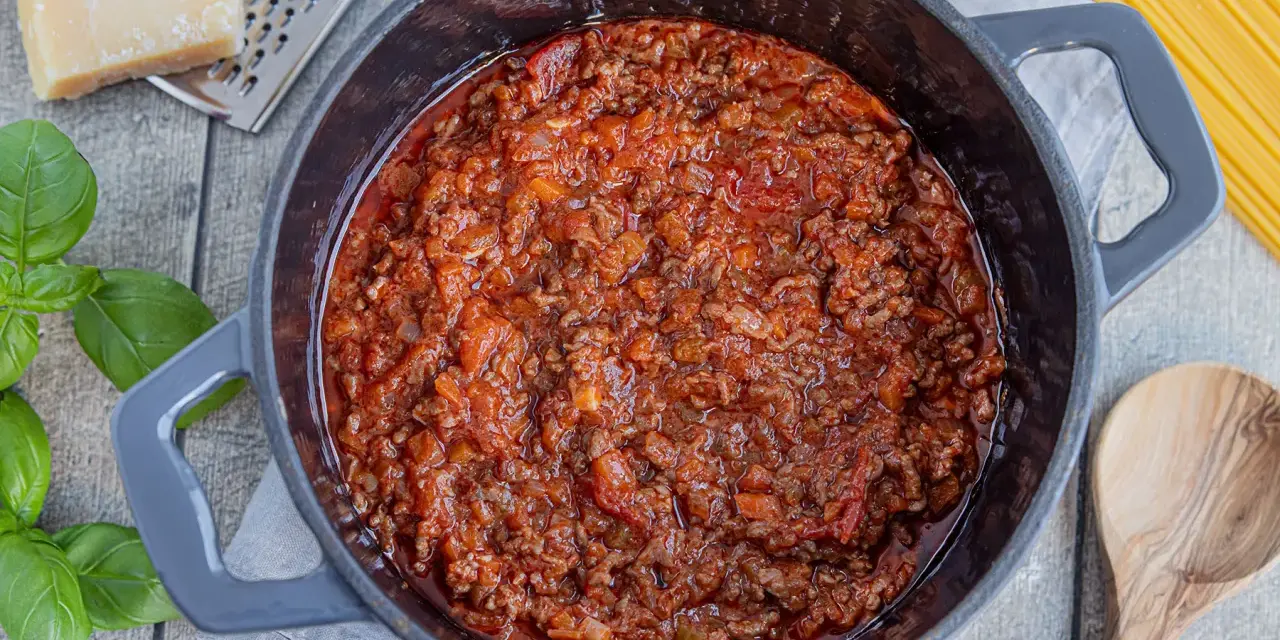 Herzhafte, beste Bolognese original im Topf, mit frischem Basilikum, Parmesan und Spaghetti daneben.
