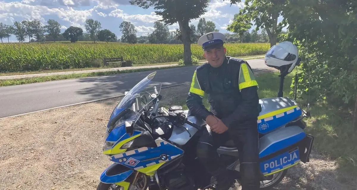 Policjant w pełnym umundurowaniu siedzi na swoim policyjnym motocyklu, gotowy do służby.