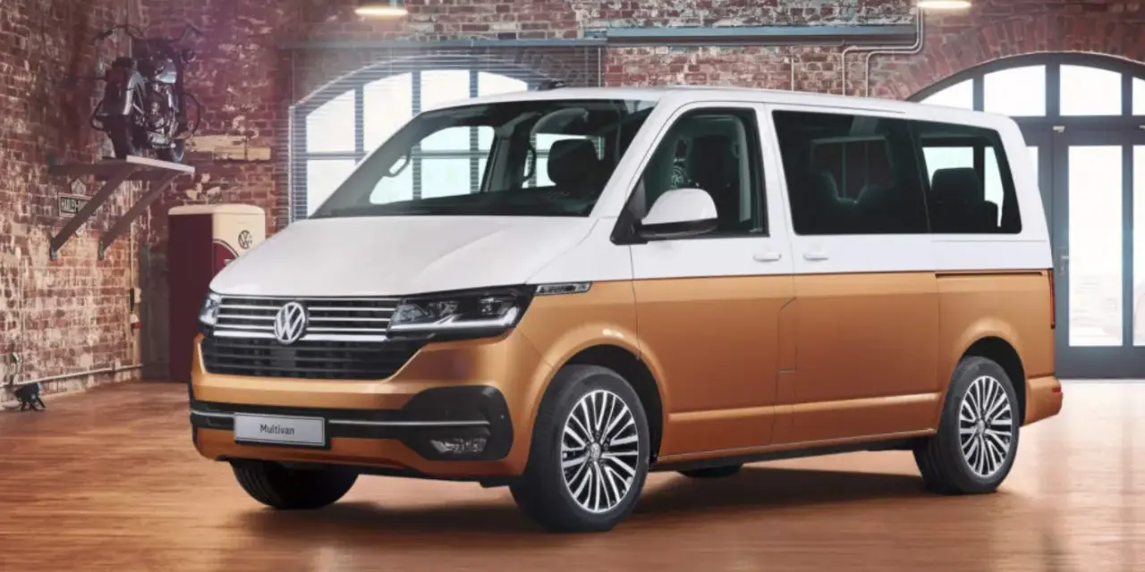Biało-złoty bus osobowy Volkswagen Multivan w garażu z ceglaną ścianą.