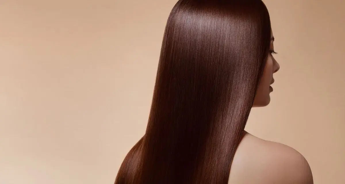 Chevelure soyeuse d'un brun profond, couleur douglas, tombant en cascade sur l'épaule d'une femme.