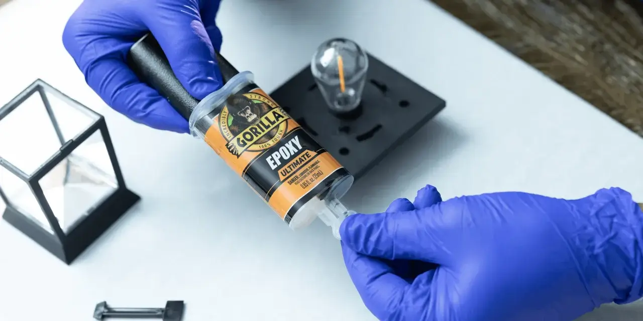 Gloves prepare to apply Gorilla Epoxy, known for its incredible strength, to a small glass and metal object.