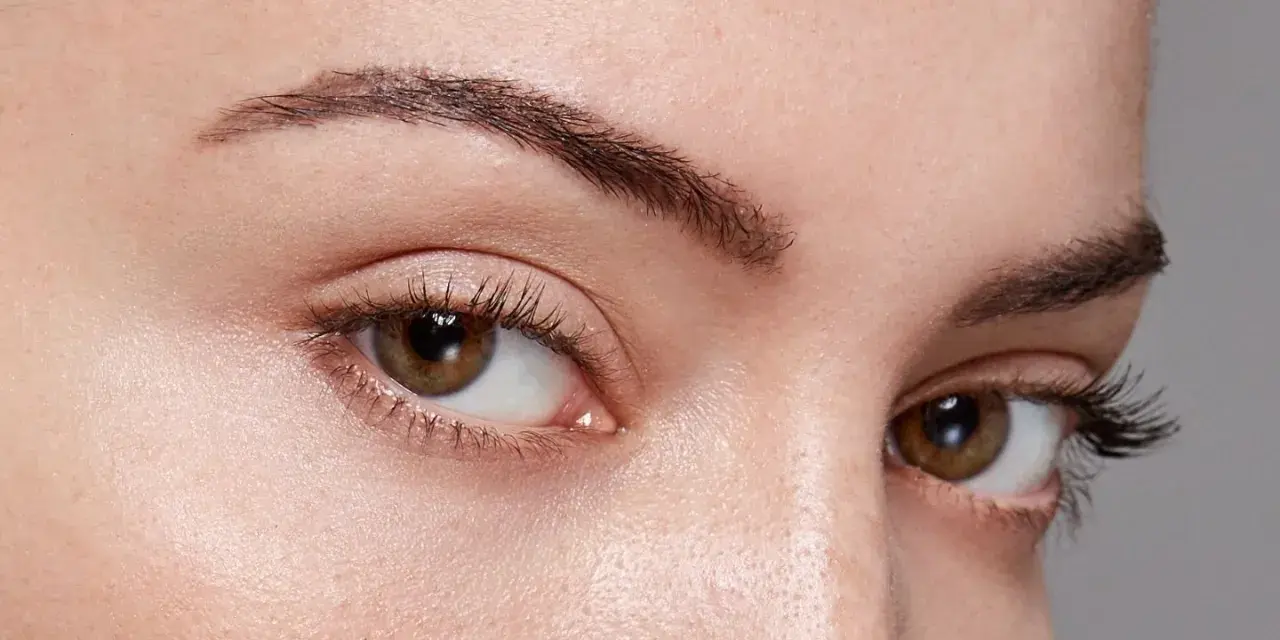 Gros plan sur des yeux aux cils longs et recourbés, encadrés par des sourcils aux forme sourcils parfaits.