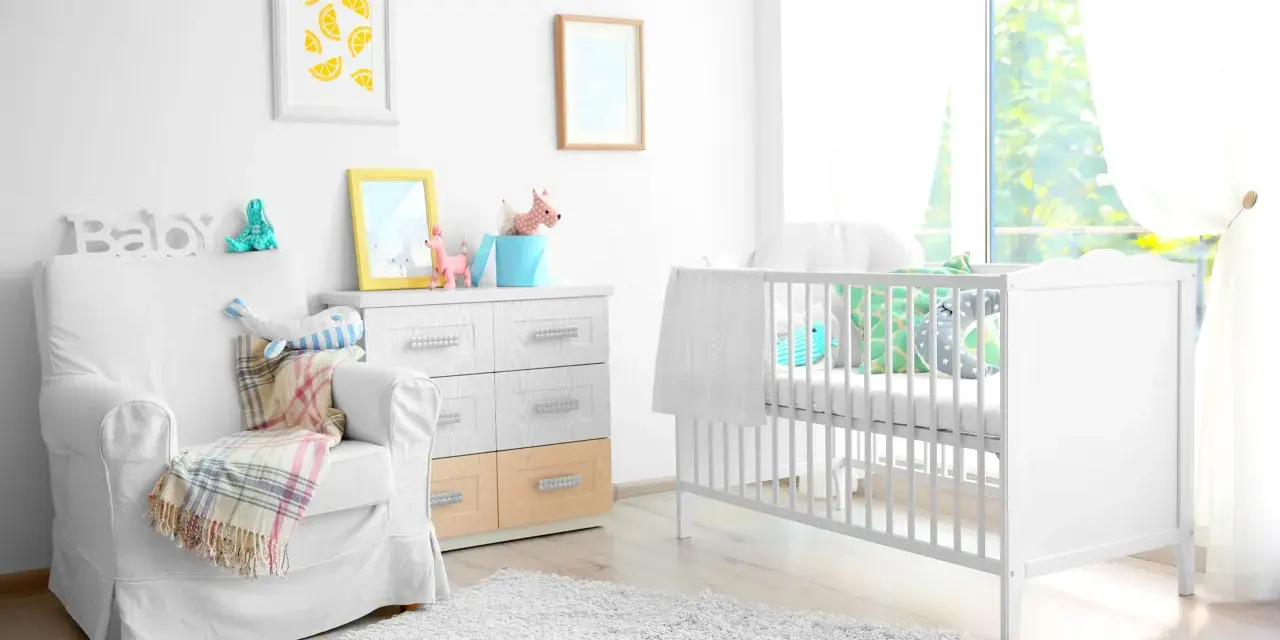 Stanza luminosa con lettino bianco, poltrona comoda e decorazioni a tema neonato. Un nido accogliente per un piccolo tesoro.