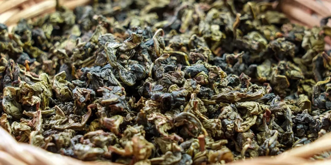 Suszone liście herbaty gunpowder w wiklinowym koszyku. Odkryj jej niezwykłe właściwości!