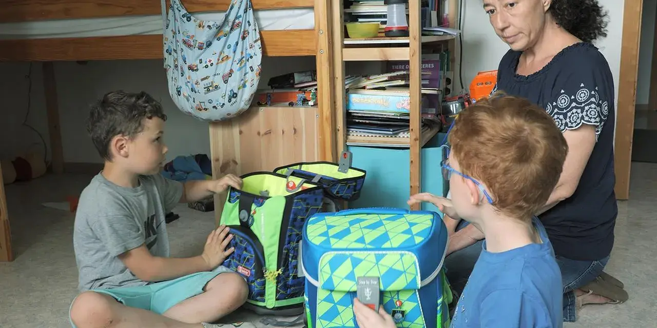 Mutter hilft ihren beiden Söhnen, Schultaschen zu packen. Ein Junge ist 16 Jahre alt.