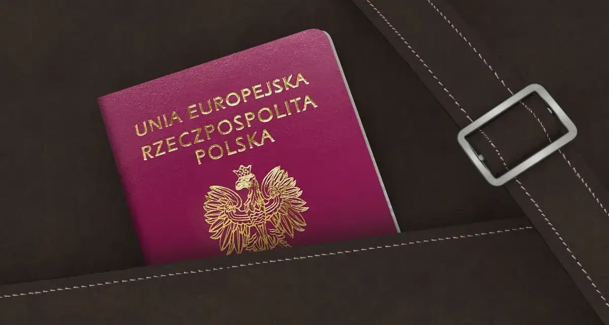 Nowy polski paszport w kolorze fuksji z godłem orła w złocie, schowany w brązowej skórzanej kieszeni.
