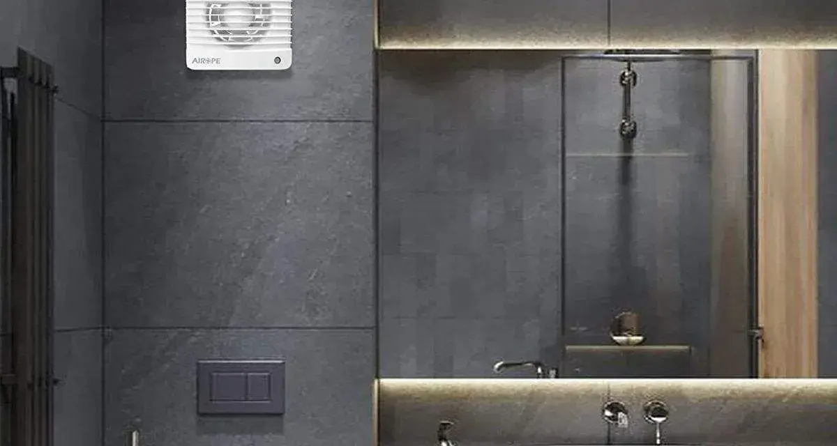 Extractor de baño blanco instalado en pared de azulejos grises.