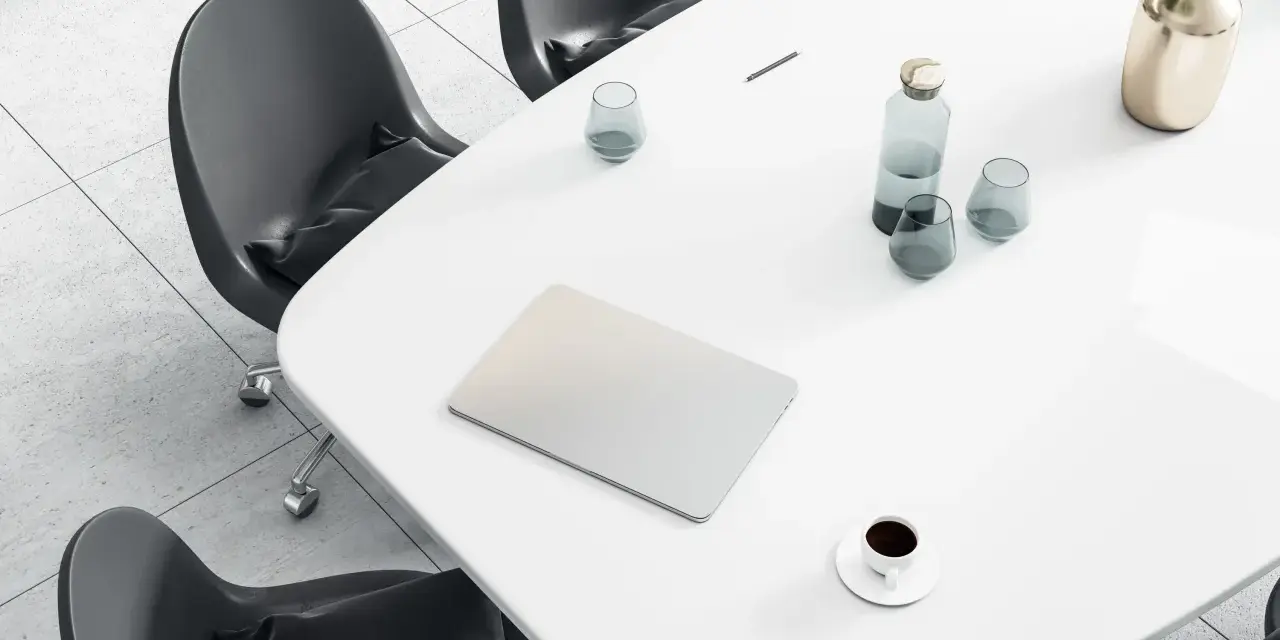 Tavolo da riunione con laptop, bicchieri d'acqua, caffè e un vaso di fiori. Ideale per un ingegnere gestionale lavoro.