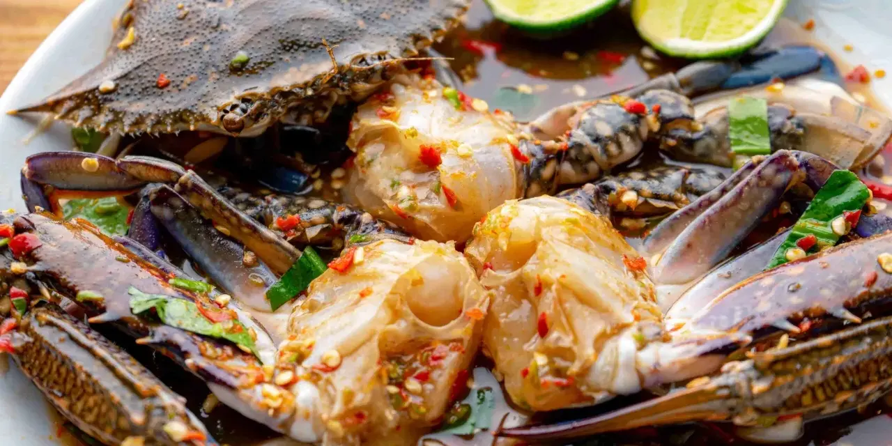 Un piatto di granchio blu crudo marinato con lime, peperoncino e erbe aromatiche. Un sapore intenso e piccante.