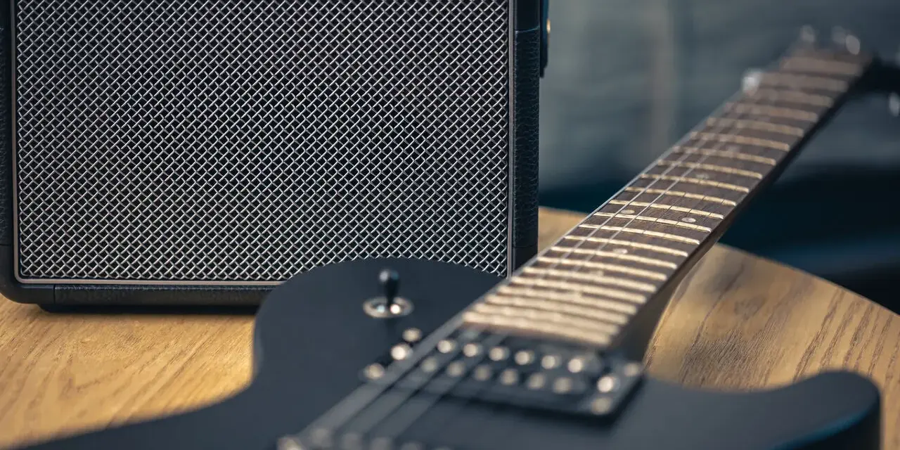 Czarna gitara elektryczna i mały wzmacniacz – to podstawa, co jest potrzebne do gitary elektrycznej, by zacząć grać.