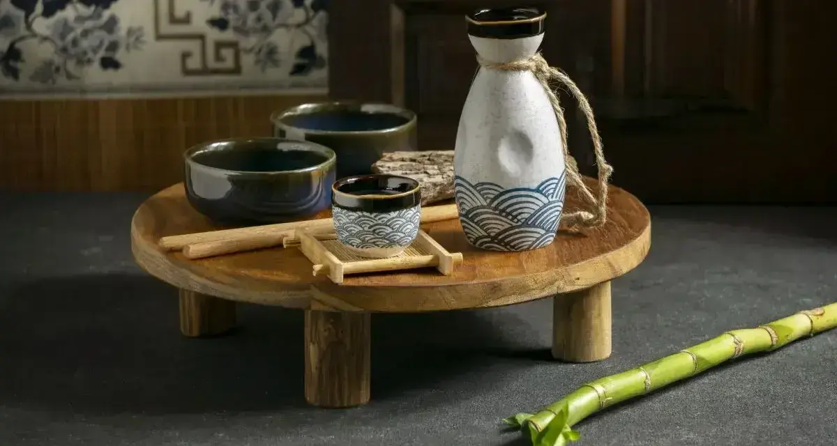 Zestaw do sake: ceramiczna butelka z falami, małe czarki i pałeczki.