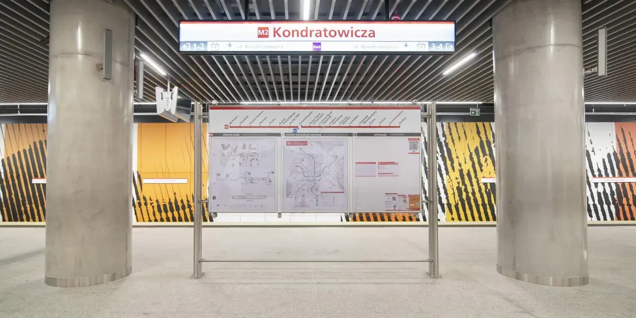 Tablica informacyjna na stacji **metro M2** Kondratowicza. Widoczne schematy stacji, sieci metra i informacje.