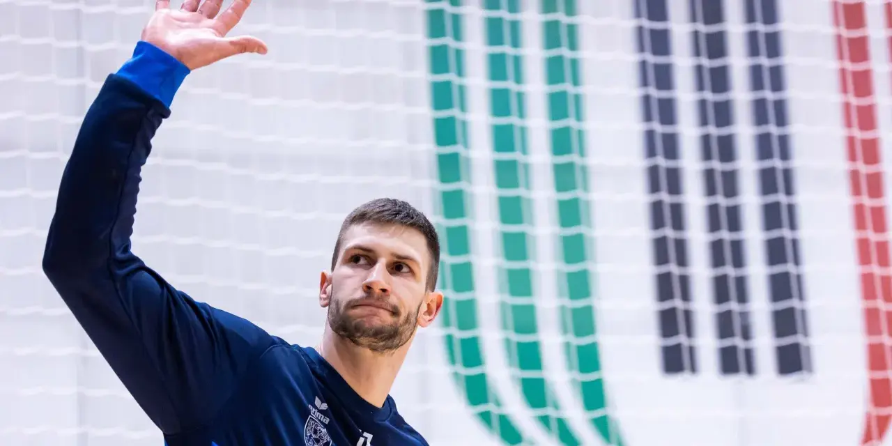 Michał Przybylak wita kibiców, unosząc dłoń.