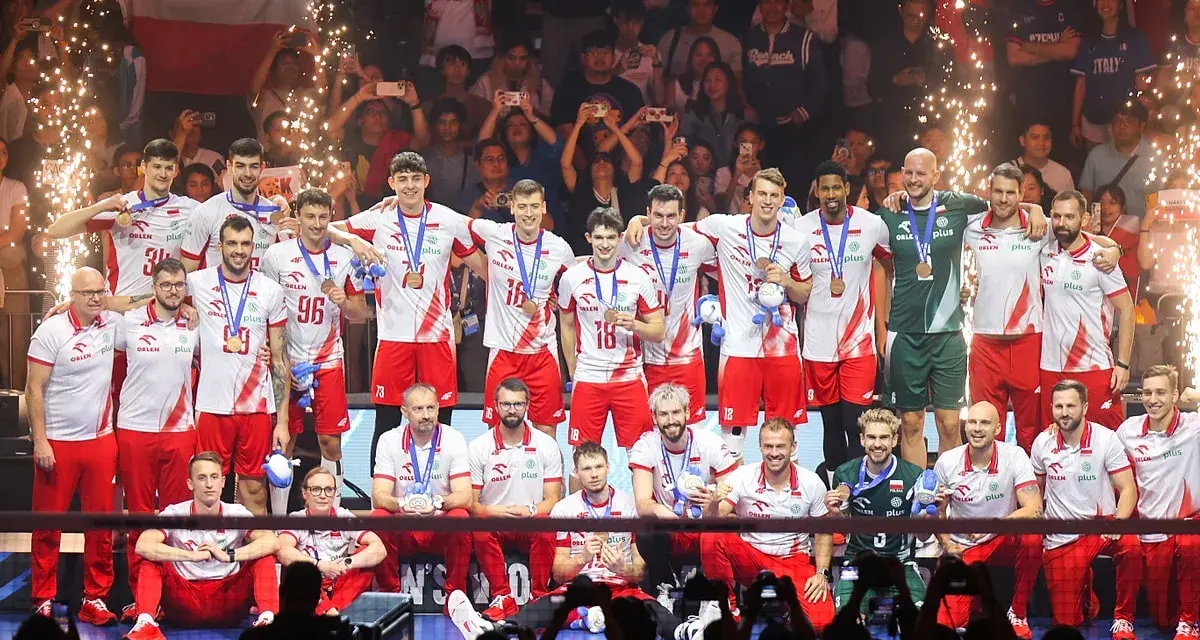 Polscy siatkarze świętują sukces na mistrzostwach świata w siatkówce 2026, z medalami na szyjach i flagą narodową w tle.