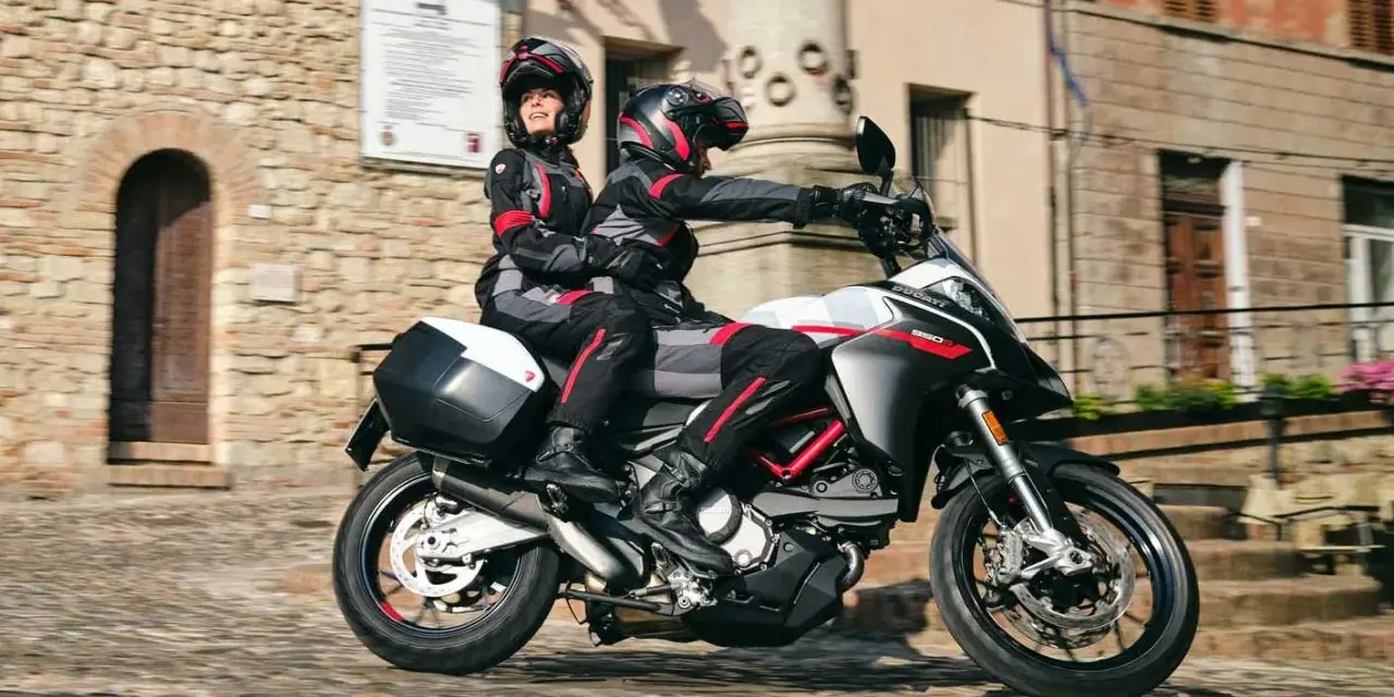 Para jadąca na sportowym motocyklu Ducati przez urokliwe, brukowane uliczki.