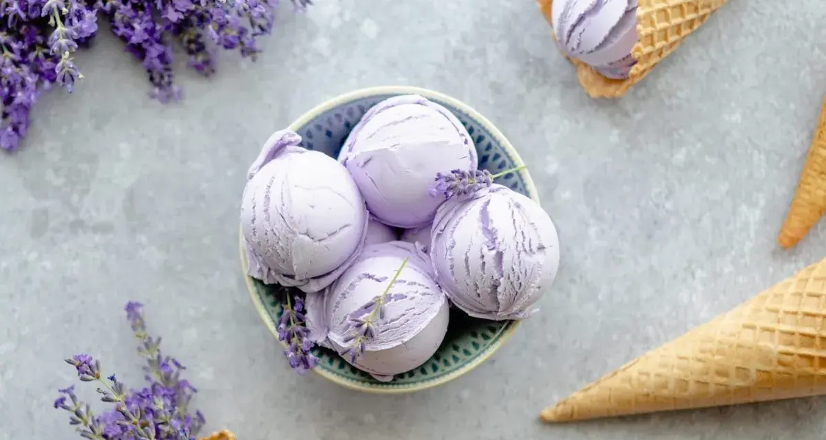 Schalen und Waffelkegel mit cremigem Lavendeleis, garniert mit frischen Lavendelzweigen.