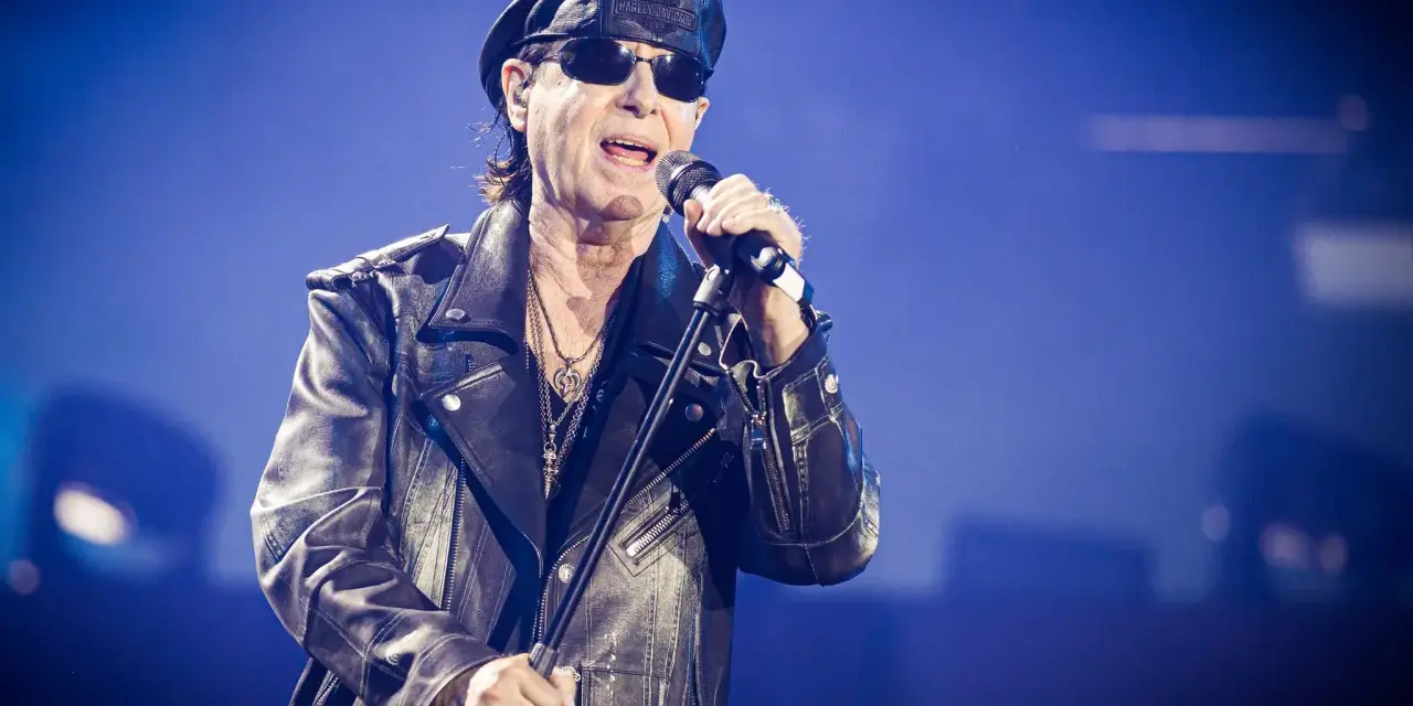 Klaus Meine, jung und rockig, singt ins Mikrofon, trägt Lederjacke und Kappe.