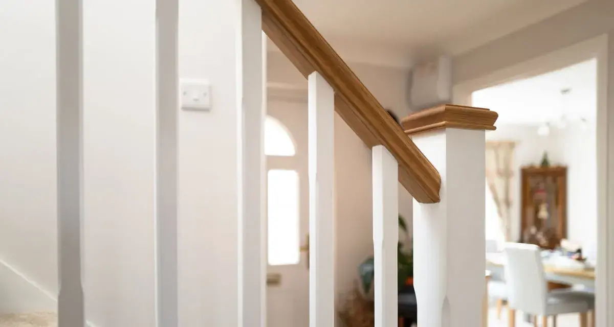 Barandilla de escalera blanca con pasamanos de madera, ideal para saber como modernizar una barandilla de madera.