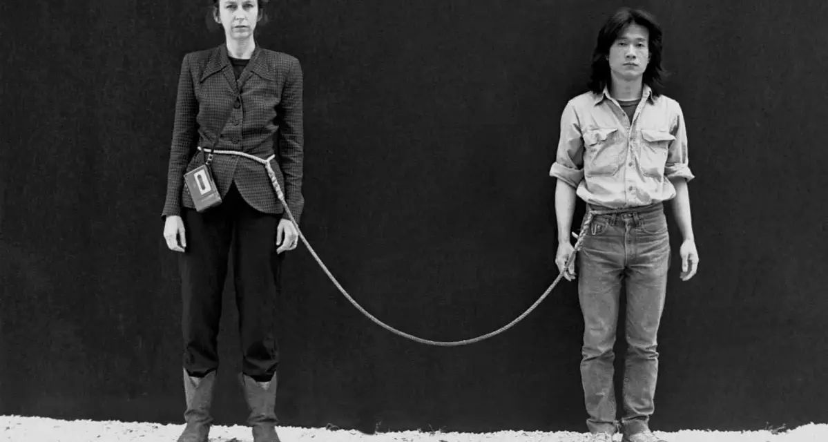 Une femme et un homme, reliés par une corde, dans une performance artistique saisissante.