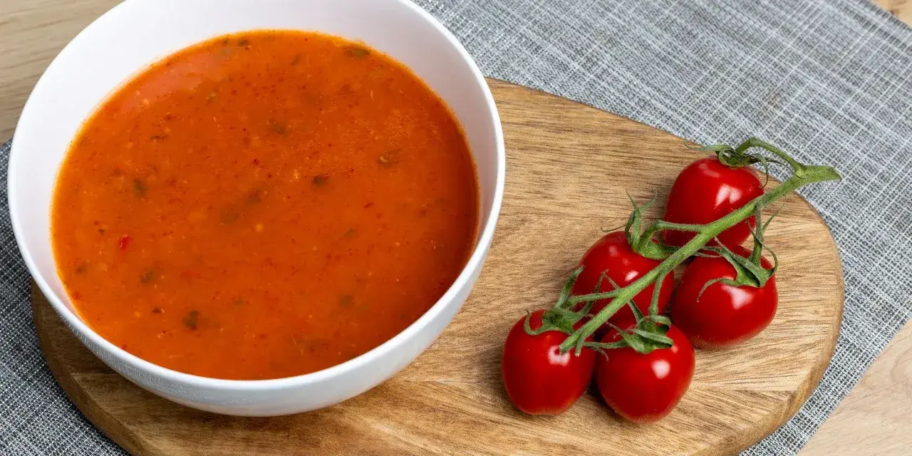 Aksamitna zupa pomidorowa z ryżem czy z makaronem? Na desce leżą świeże pomidorki koktajlowe, idealne do tej klasycznej potrawy.